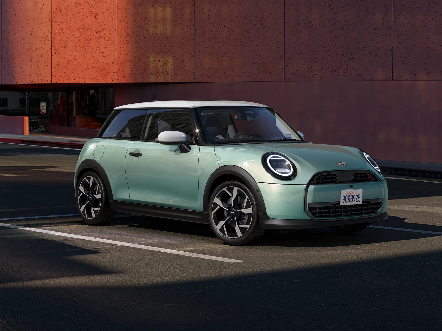 Sivunäkymä edestä MINI Cooperista Ocean Wave Green -värissä ja valkokattoisena.