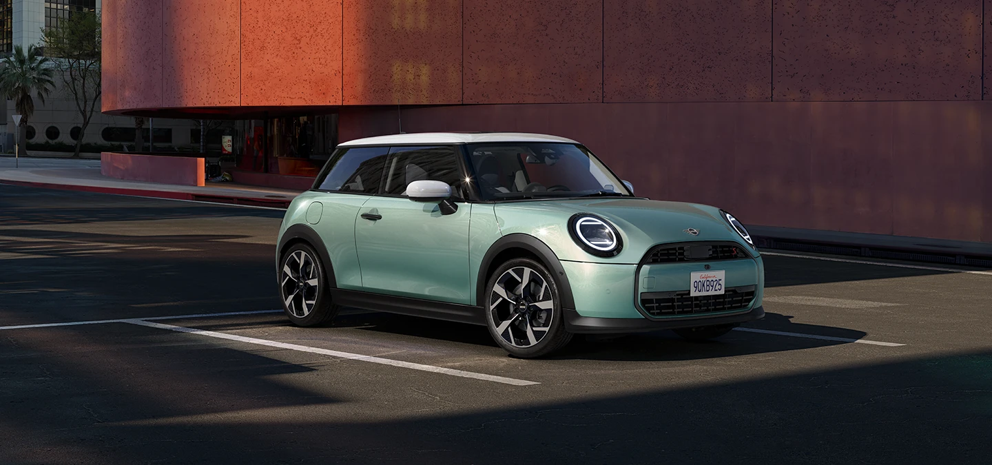 Sivunäkymä edestä MINI Cooperista Ocean Wave Green -värissä ja valkokattoisena.