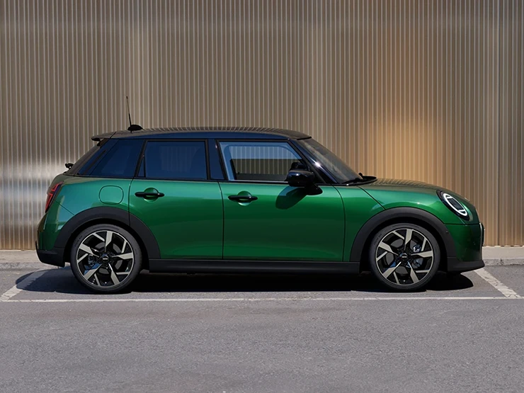 Sivukuva British Racing Green -värisestä ja mustakattoisesta 5-ovisesta MINI Cooperista pysäköitynä.
