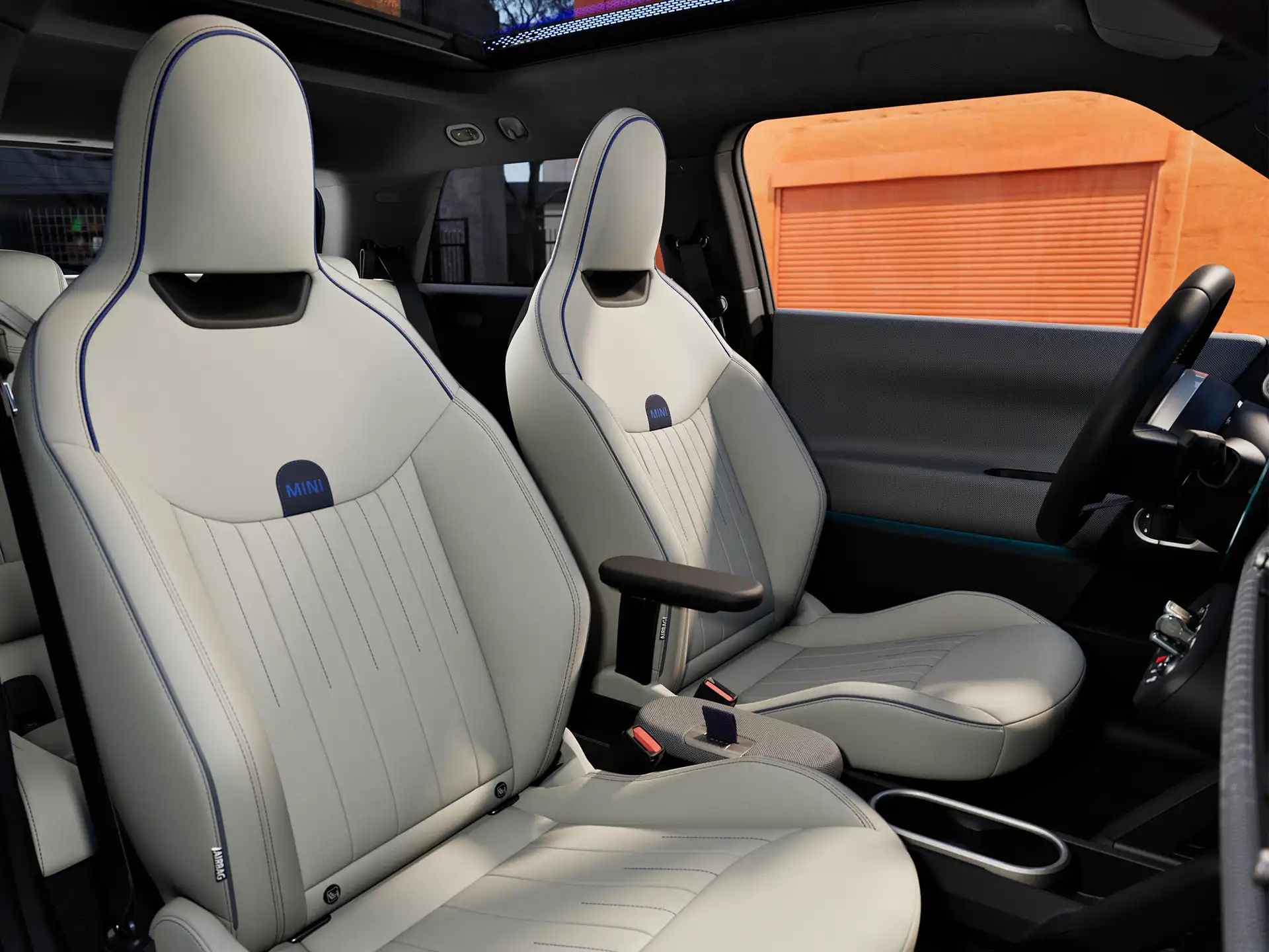 Täyssähköisen MINI Cooperin sisäkuva, jossa näkyy kojelauta, ohjauspyörä, pyöreä näyttö, lasikatto ja etuistumien takaosat