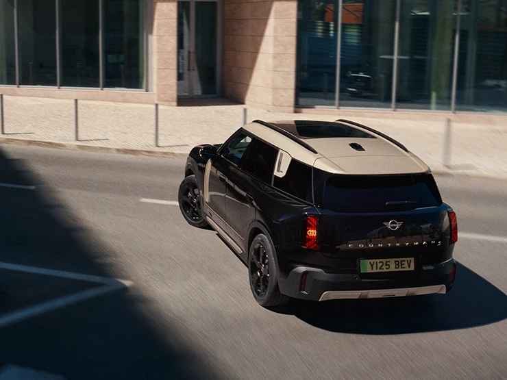 Näkymä takaa ylhäältä pysäköidystä täyssähköisestä MINI Countrymanista Smokey Green -värissä ja Vibrant Silver -katolla.