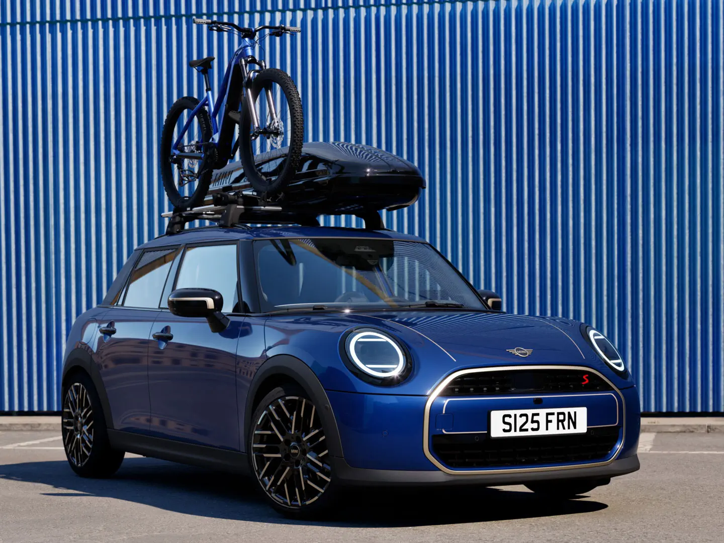 Kuva edestä Indigo Sunset Blue -värisestä MINI Acemanista MINI-kattopyörätelineellä, jossa on maastopyörä ja MINI-kattoboksi 320.