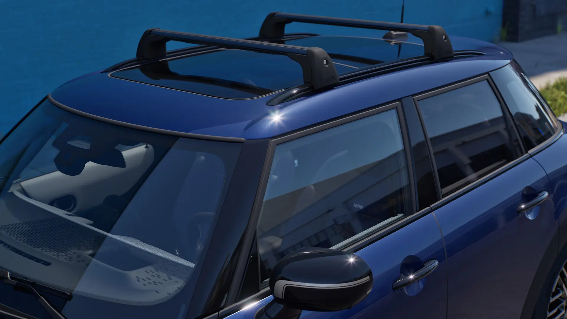 Edestä ja sivusta otettu lähikuva MINIn kattotelineellä varustetusta Indigo Sunset Blue -värisestä MINI Acemanista. 