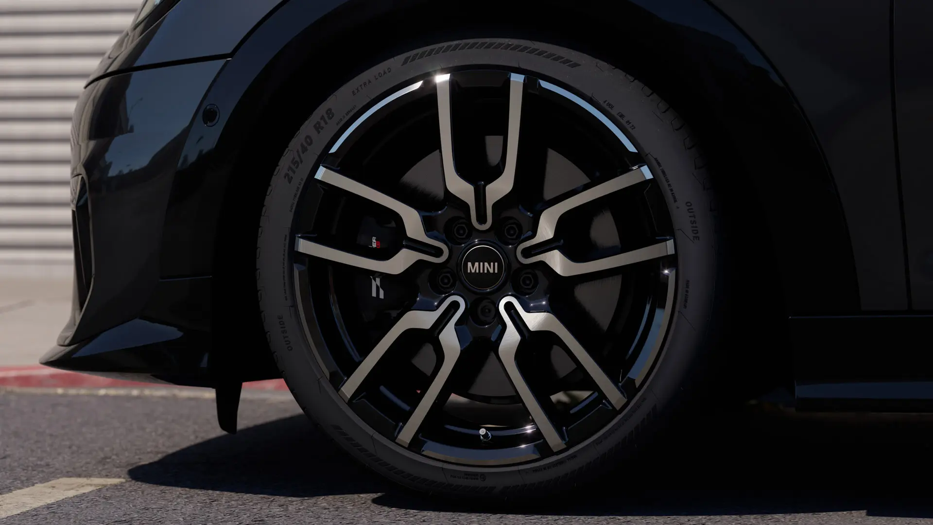 Lähikuva JCW Lap Spoke ‑kevytmetallivanteesta, jossa näkyy sen erottuva avoimen puolan muotoilurakenne Jet Black ‑viimeistelyllä. 