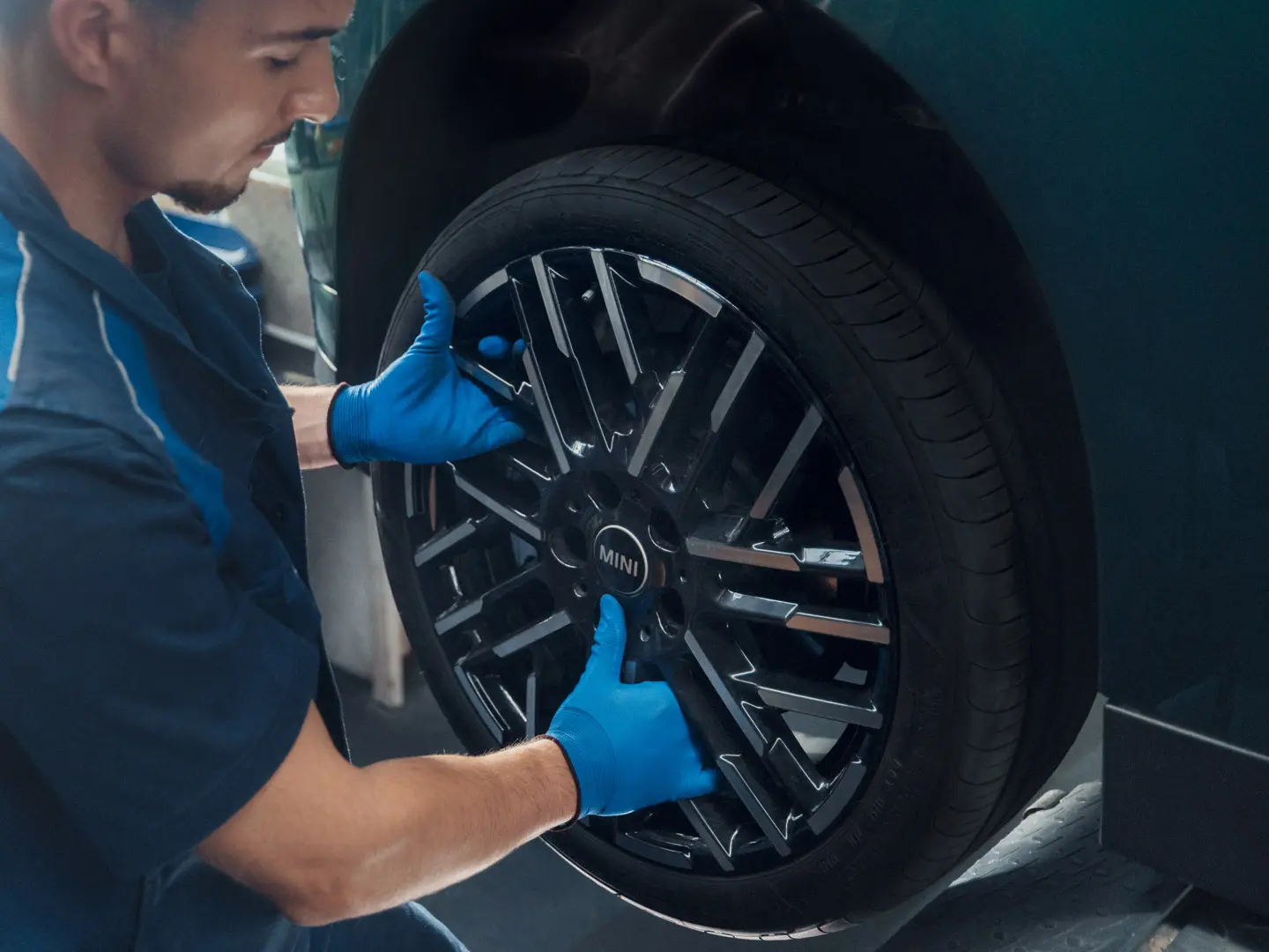 MINI-huoltomekaanikko asentaa MINI 18" Night Flash Spoke Bicolour ‑kevytmetallivannetta MINI Cooper Electric -malliin.