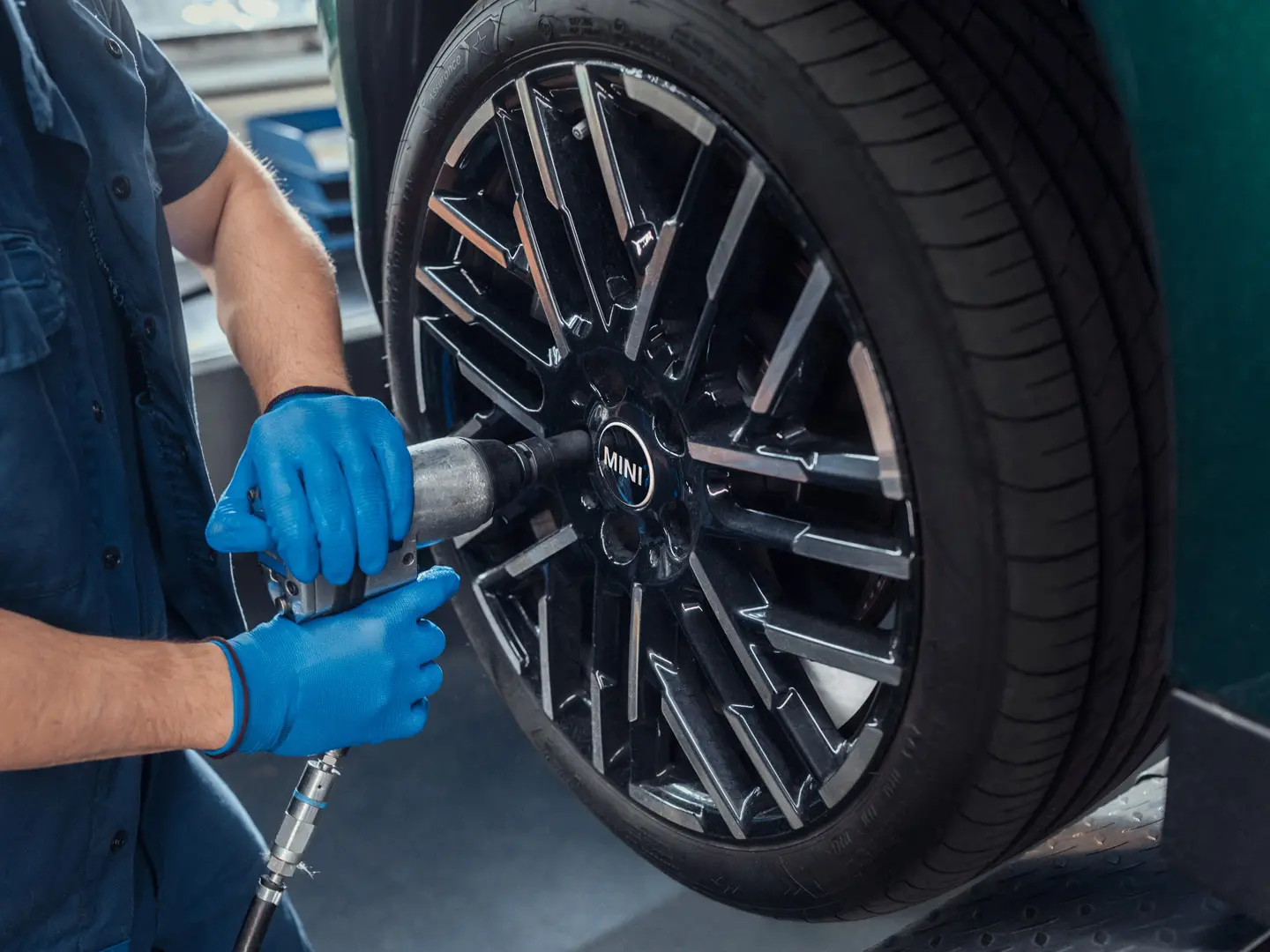 MINI Partnerin huoltomekaanikko asentaa 18" Night Flash Spoke Bicolour ‑kevytmetallivanteen MINIin.