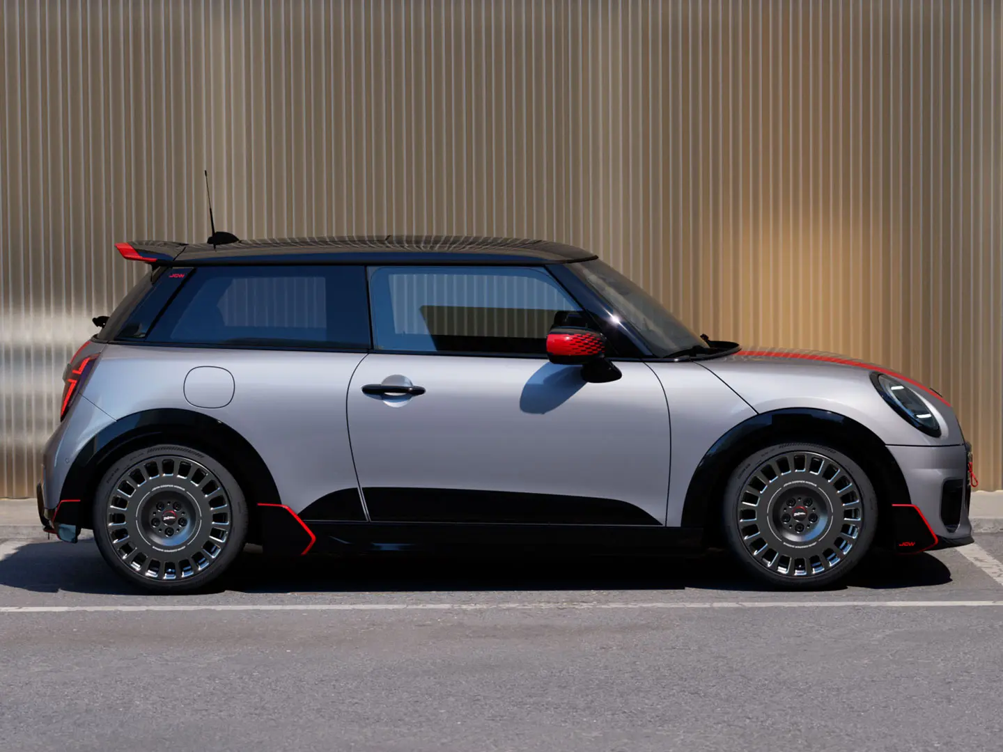 MINI Cooper, 3-ovinen, väri Melting Silver – John Cooper Works ‑kattospoileri, joka parantaa aerodynaamisia ominaisuuksia – sivunäkymä.