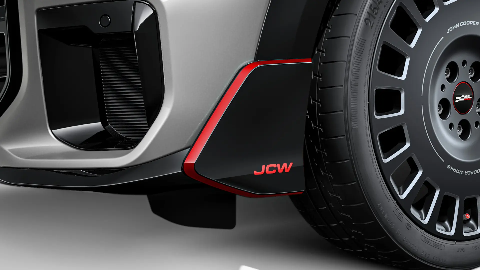 MINI John Cooper Works ‑etusiiveke korkeakiiltoisen mustana, punaisilla JCW-kirjaimilla ja tehosteraidoilla.