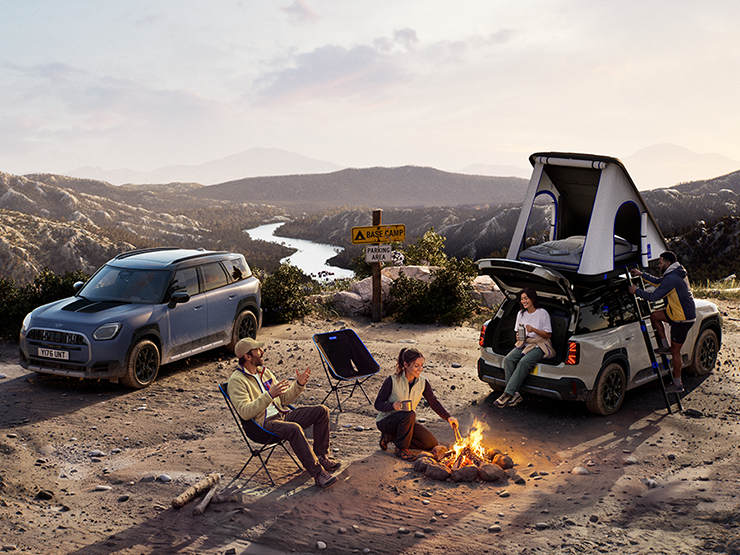 Kuva kahdesta MINI Countryman Untamed Edition -ajoneuvosta vuorella auringonlaskun aikaan.