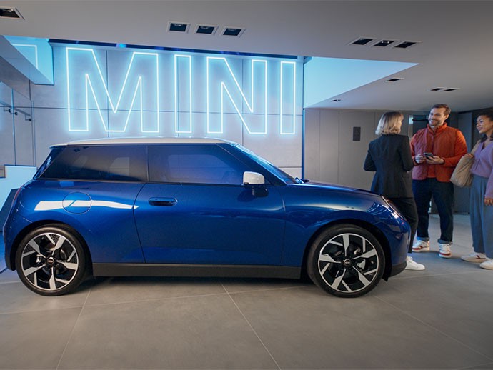 MINI Cooper sähköinen näkymä takaa ja hymyilevä nainen
